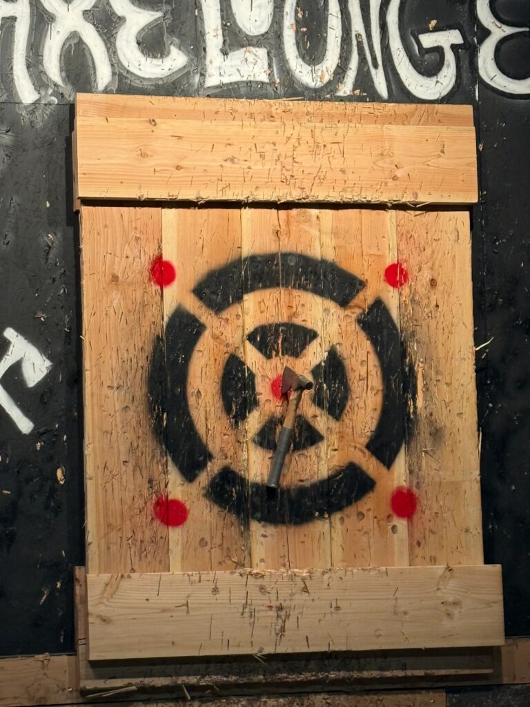 A small throwing axe stuck directly in the red bullseye of a wooden target at Kings Eye Axes in Costa Mesa, CA.