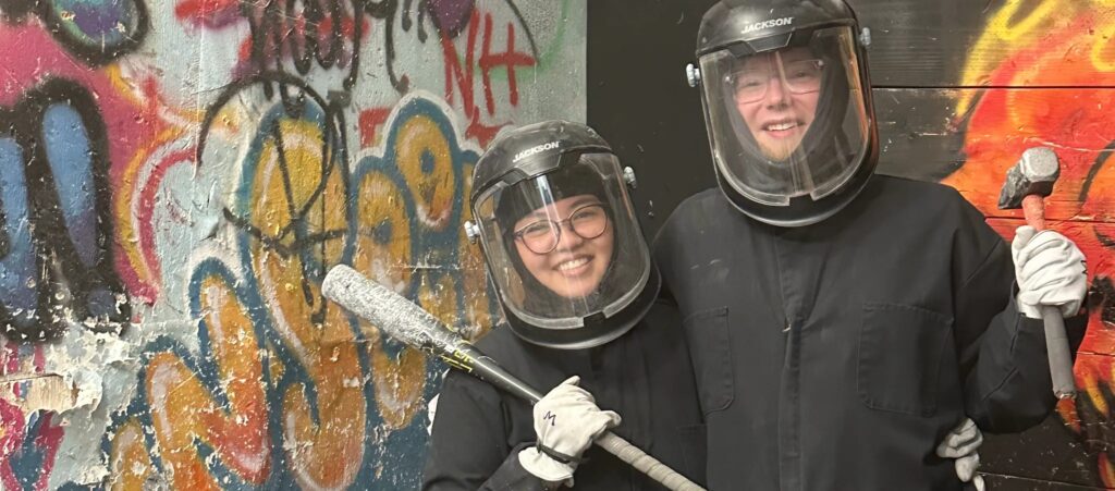 A happy couple posing with throwing axes during a date night at Kings Eye Axes in Costa Mesa, CA.