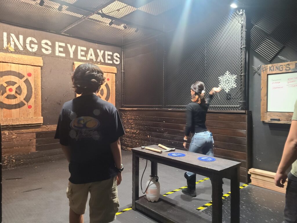 Two professional axe throwing lanes with wooden targets and branded "#KINGS EYE AXES" signage in Costa Mesa, CA.